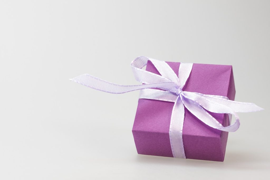 Purple gift box wrapped in light lavender bow with white background