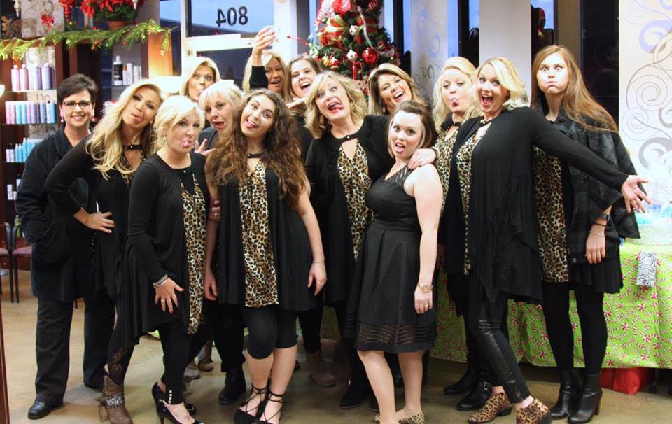 Group of fourteen women dressed in black and leopard print making silly expressions