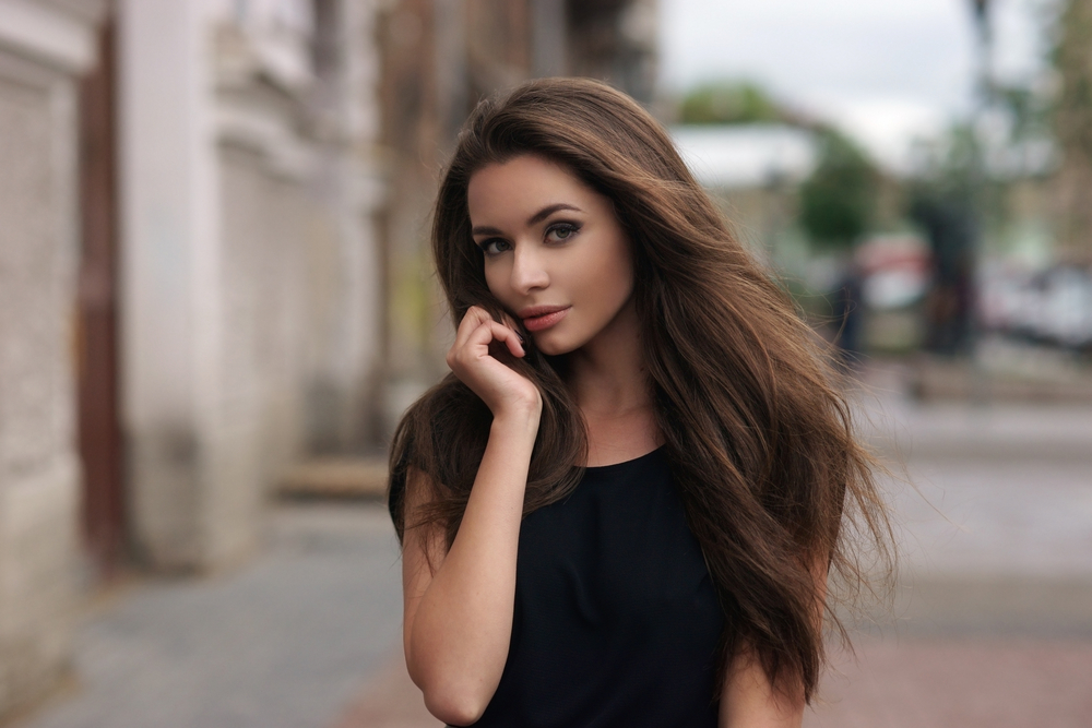 Young beautiful woman on street with long brown hair and black shirt