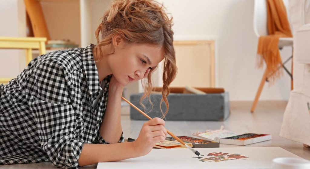 Woman laying on the floor painting