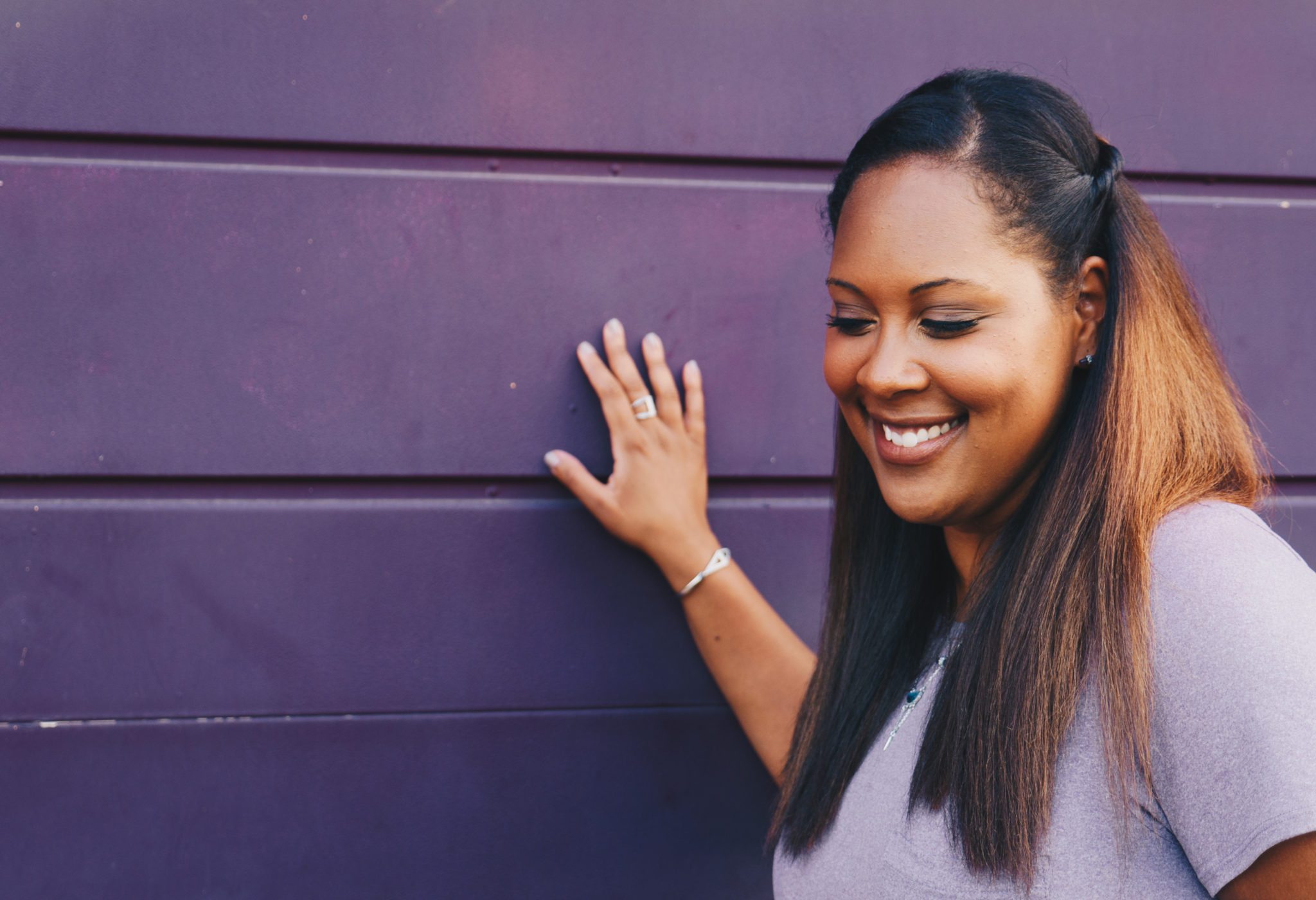 woman smiling and standing in front of a purple wall