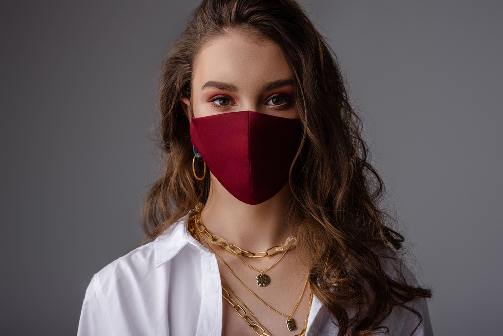 young woman modeling a facemask with red eyeshadow and gold jewelry with white shirt