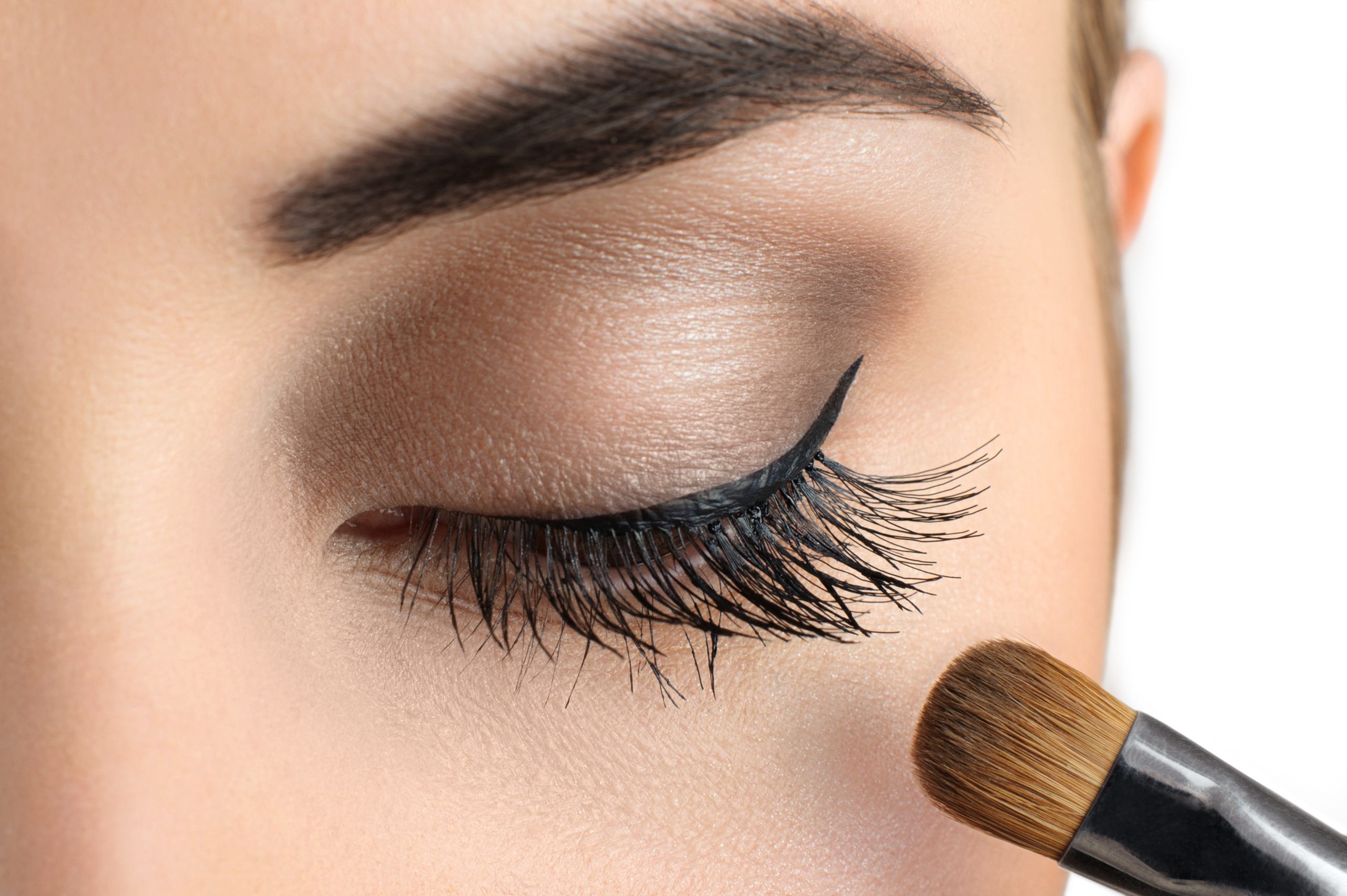 flat eyeshadow brush in front eyelashes of a woman with her makeup done