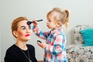 blonde child giving her mother a makeover