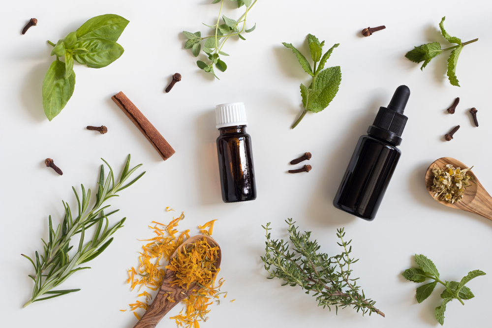 essential oils wth a selection of herbs on white background